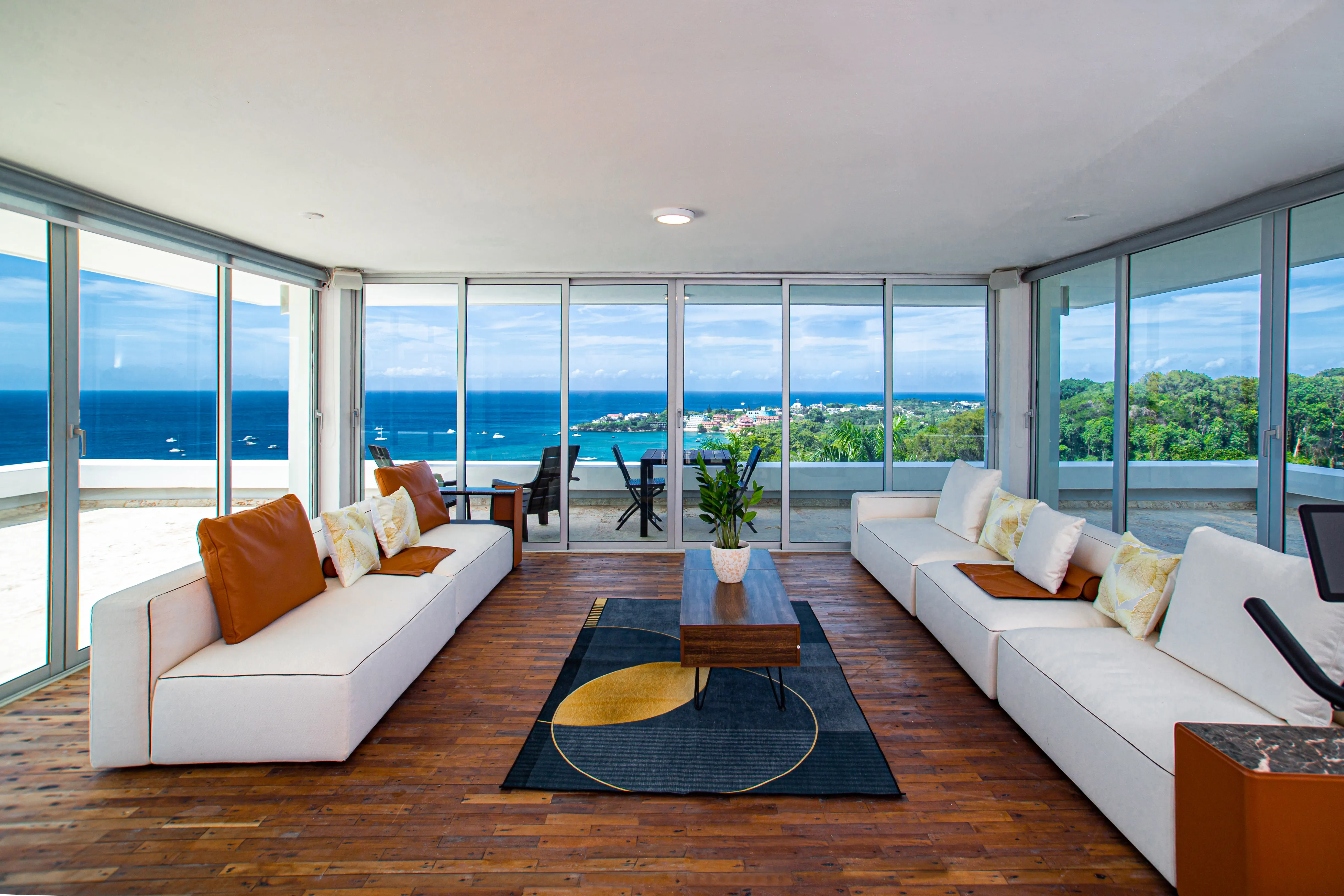 Top-floor living room with twin sofas and wraparound windows over the ocean