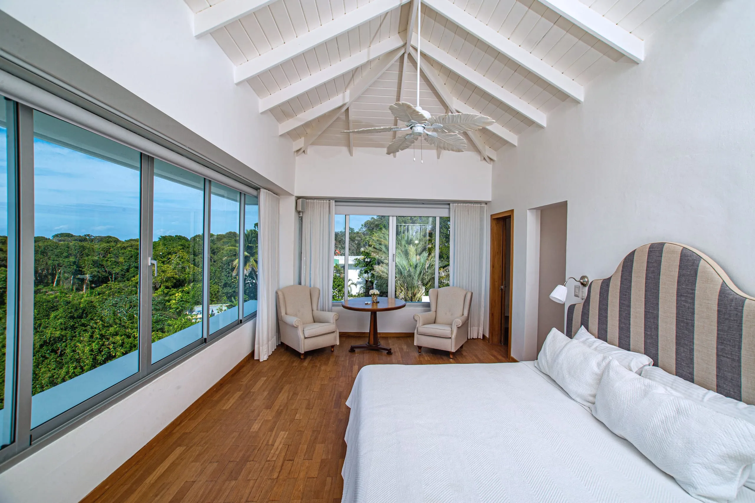 Primary suite with a vaulted wood ceiling and windows wrapping toward the treetops