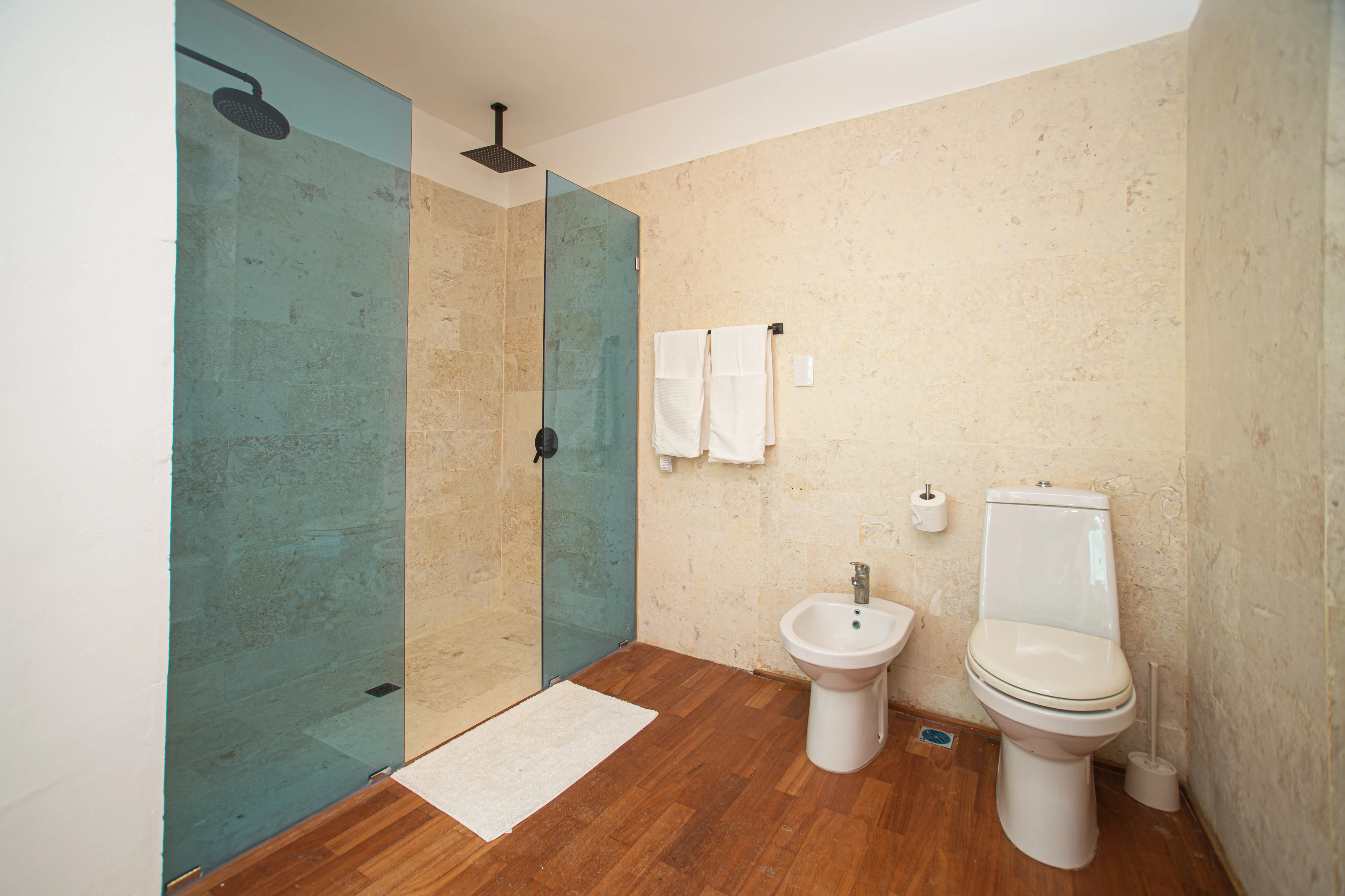Primary ensuite with a walk-in rain shower in travertine stone